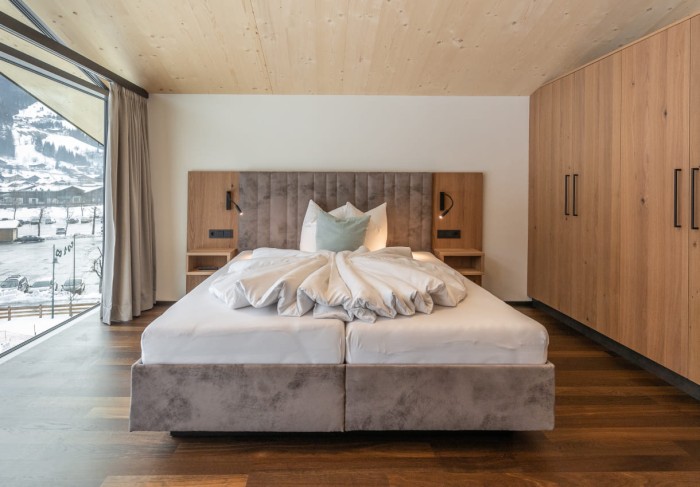 Bett mit großem Panoramafenster in der Ferienwohnung Schuhflicker von Appartements Lackner