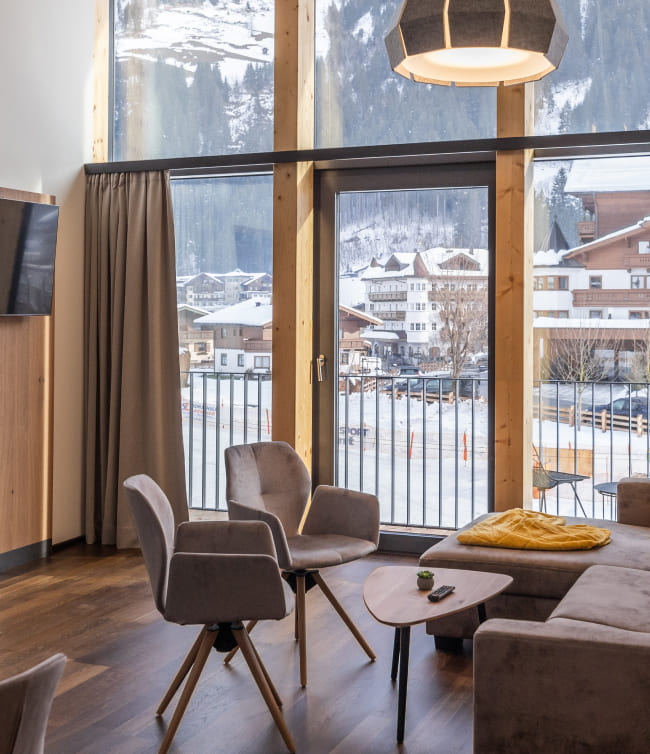 Wohnraum im Appartement mit großem Panoramafenster und Ausblick auf die Großarler Bergwelt
